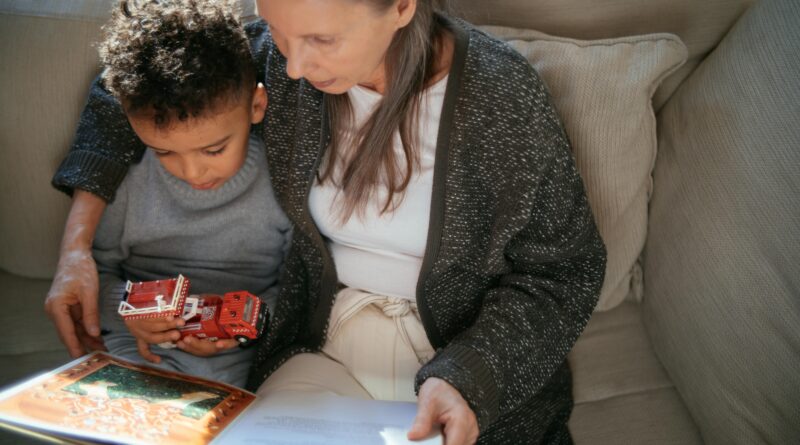 A grandmother and grandson sharing a cozy reading moment on a sofa indoors.