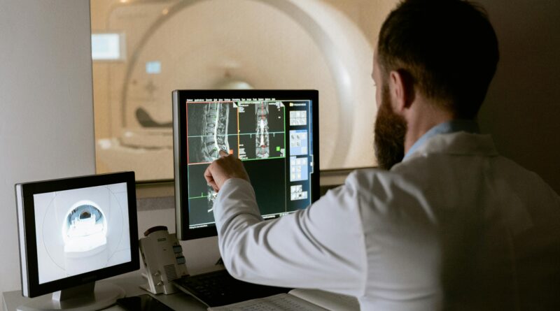 Medical professional reviewing MRI scans on computer screens for diagnostic purposes.